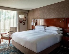 Spacious king guest room with plush bedding, floor-to-ceiling windows, and sophisticated décor at Boston Marriott Newton.