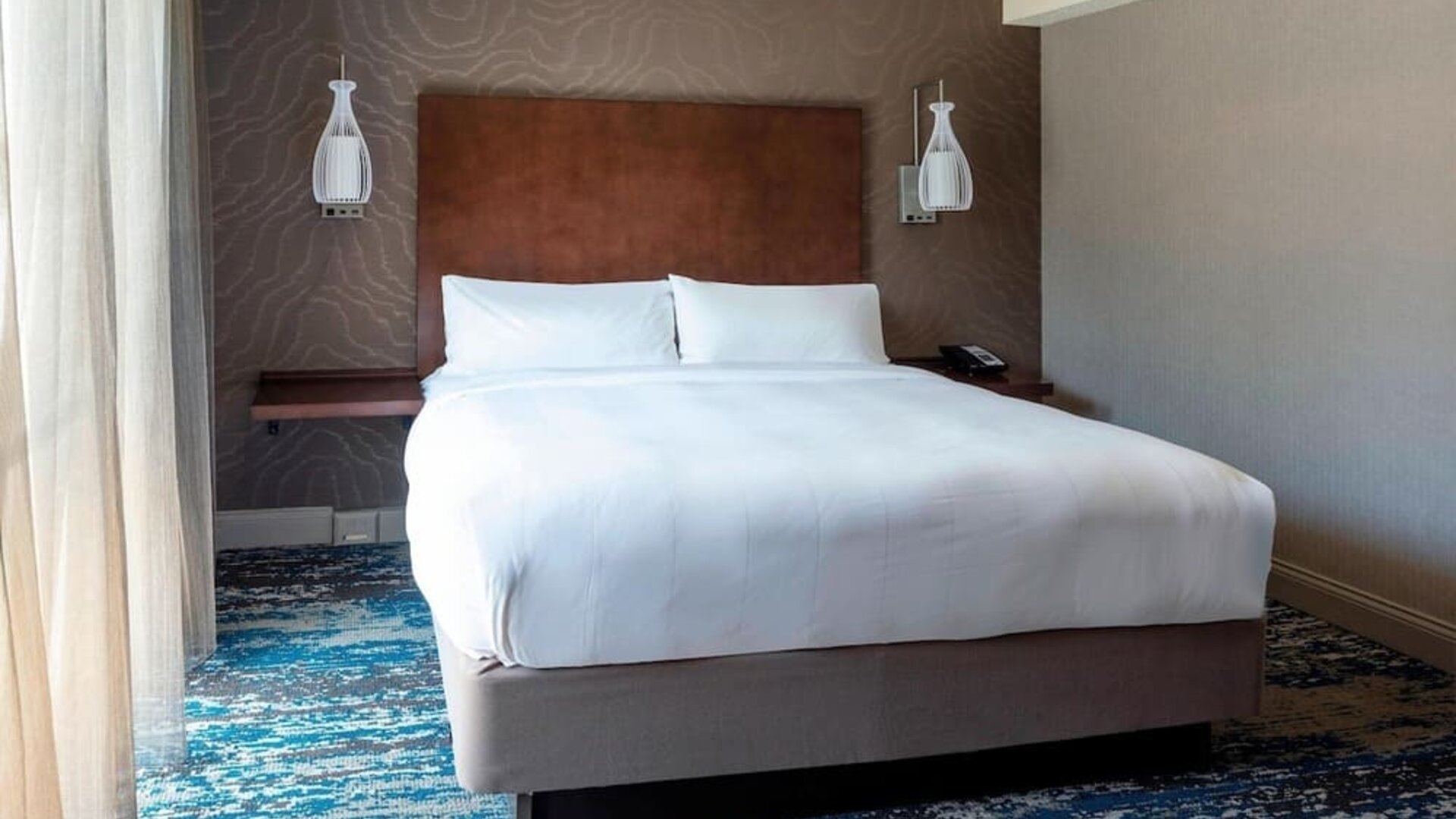 Bright king guest room with modern furnishings, large television, and relaxing natural light at Boston Marriott Newton.