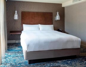 Bright king guest room with modern furnishings, large television, and relaxing natural light at Boston Marriott Newton.