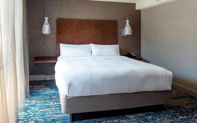 Bright king guest room with modern furnishings, large television, and relaxing natural light at Boston Marriott Newton.