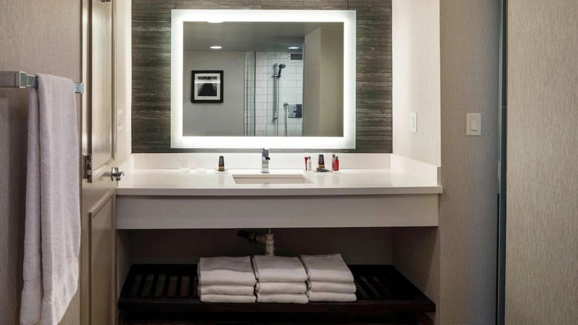 Modern guest bathroom with illuminated vanity mirror, spacious countertop, and contemporary finishes at Boston Marriott Newton.