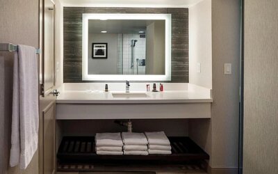 Modern guest bathroom with illuminated vanity mirror, spacious countertop, and contemporary finishes at Boston Marriott Newton.