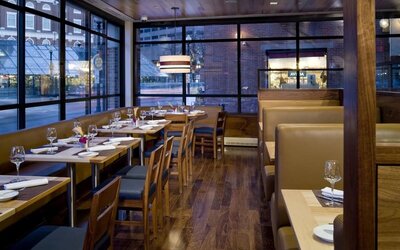 Stylish dining area with floor-to-ceiling windows, cozy booth seating, and contemporary restaurant design at The Bostonian Boston, A Millennium Hotel.