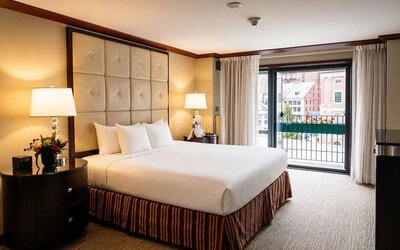 Elegant king guest room with plush bedding, spacious layout, and balcony views at The Bostonian Boston, A Millennium Hotel.