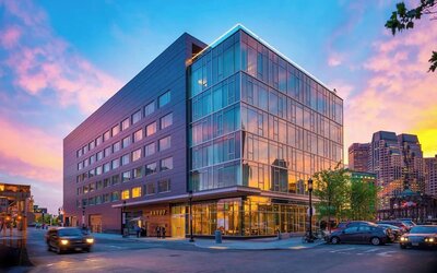 Modern glass-front hotel exterior at sunset showcasing contemporary architecture in Boston’s Seaport District at The Envoy Hotel, Autograph Collection.