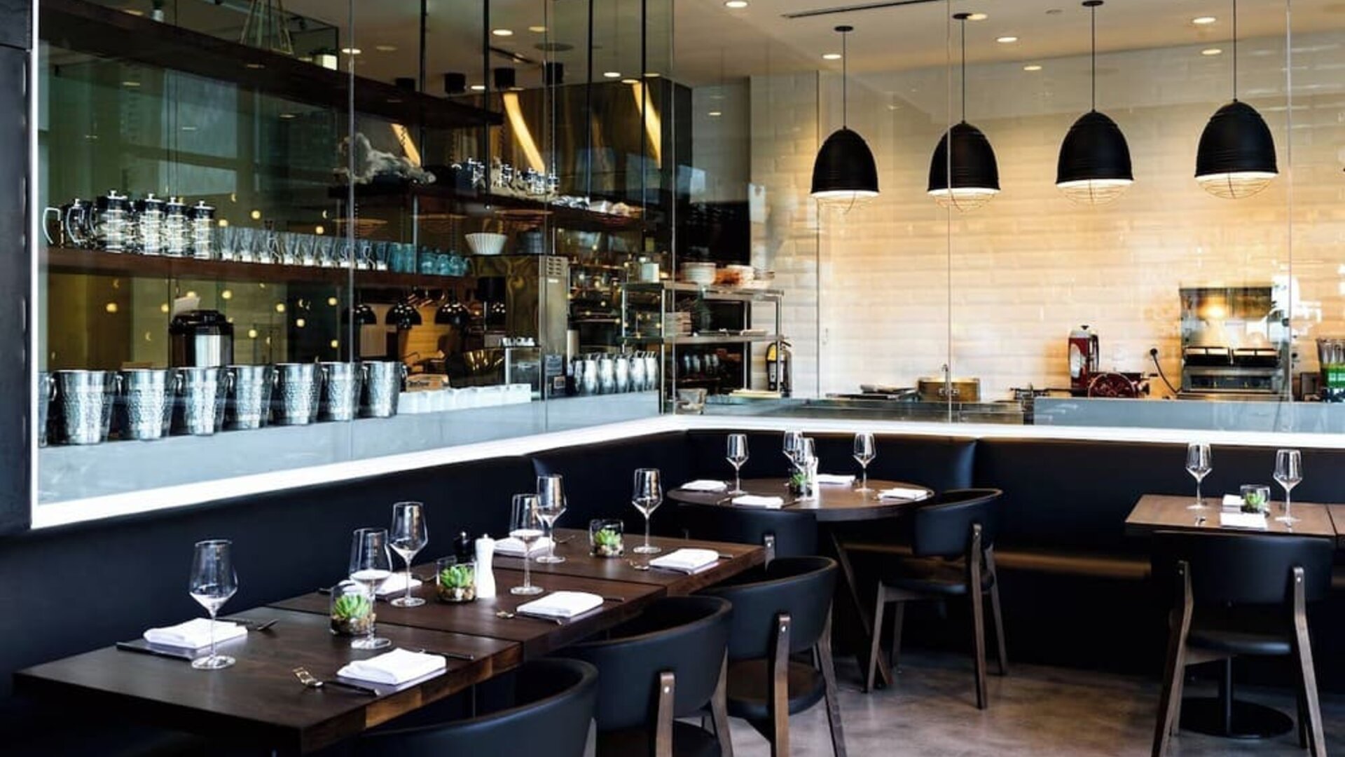 Chic restaurant dining area with open kitchen concept, elegant lighting, and contemporary seating at The Envoy Hotel, Autograph Collection.