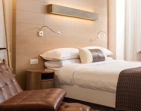 Contemporary king guest room featuring warm wood accents, plush bedding, and stylish modern furnishings at The Envoy Hotel, Autograph Collection.