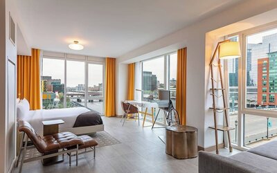 Spacious modern suite with open-plan design, city views, contemporary décor, and comfortable lounge seating at The Envoy Hotel, Autograph Collection.