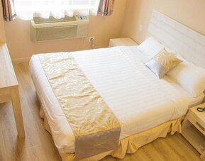 Cozy king bedroom with light wood furnishings and minimalist décor at Phoenix Hotel Brooklyn Sunset Park.