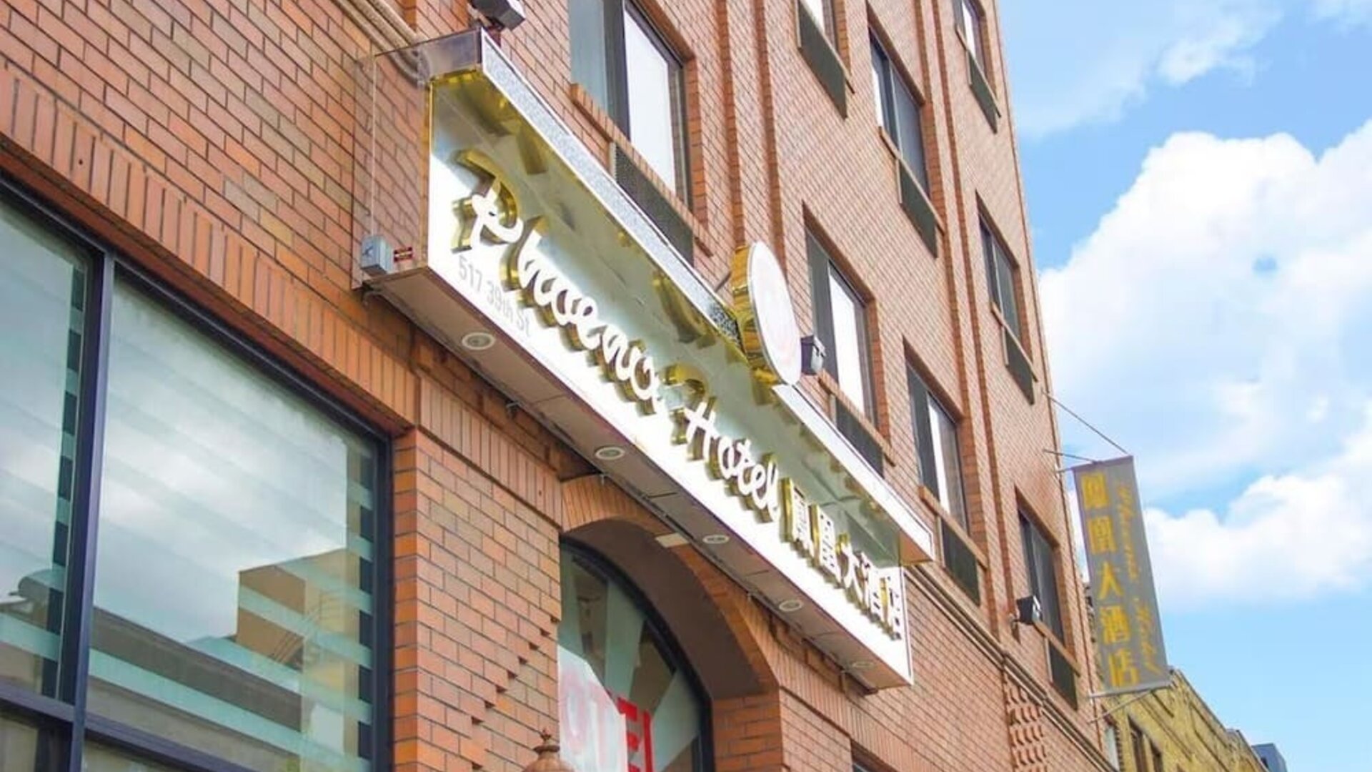 Close-up of the hotel entrance signage at Phoenix Hotel Brooklyn Sunset Park with bilingual branding and urban architectural details.
