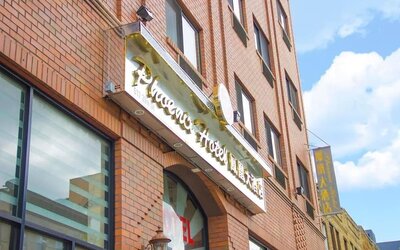 Close-up of the hotel entrance signage at Phoenix Hotel Brooklyn Sunset Park with bilingual branding and urban architectural details.