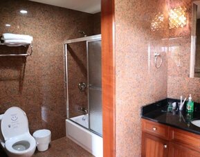 Modern bathroom with granite-style walls, glass shower enclosure, and vanity sink at Phoenix Hotel Brooklyn Sunset Park.