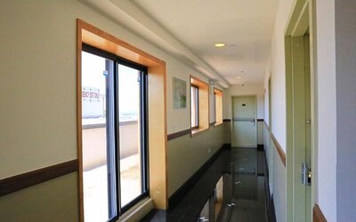 Clean and modern hotel corridor with large windows allowing natural daylight into the passageway at Phoenix Hotel Brooklyn Sunset Park.
