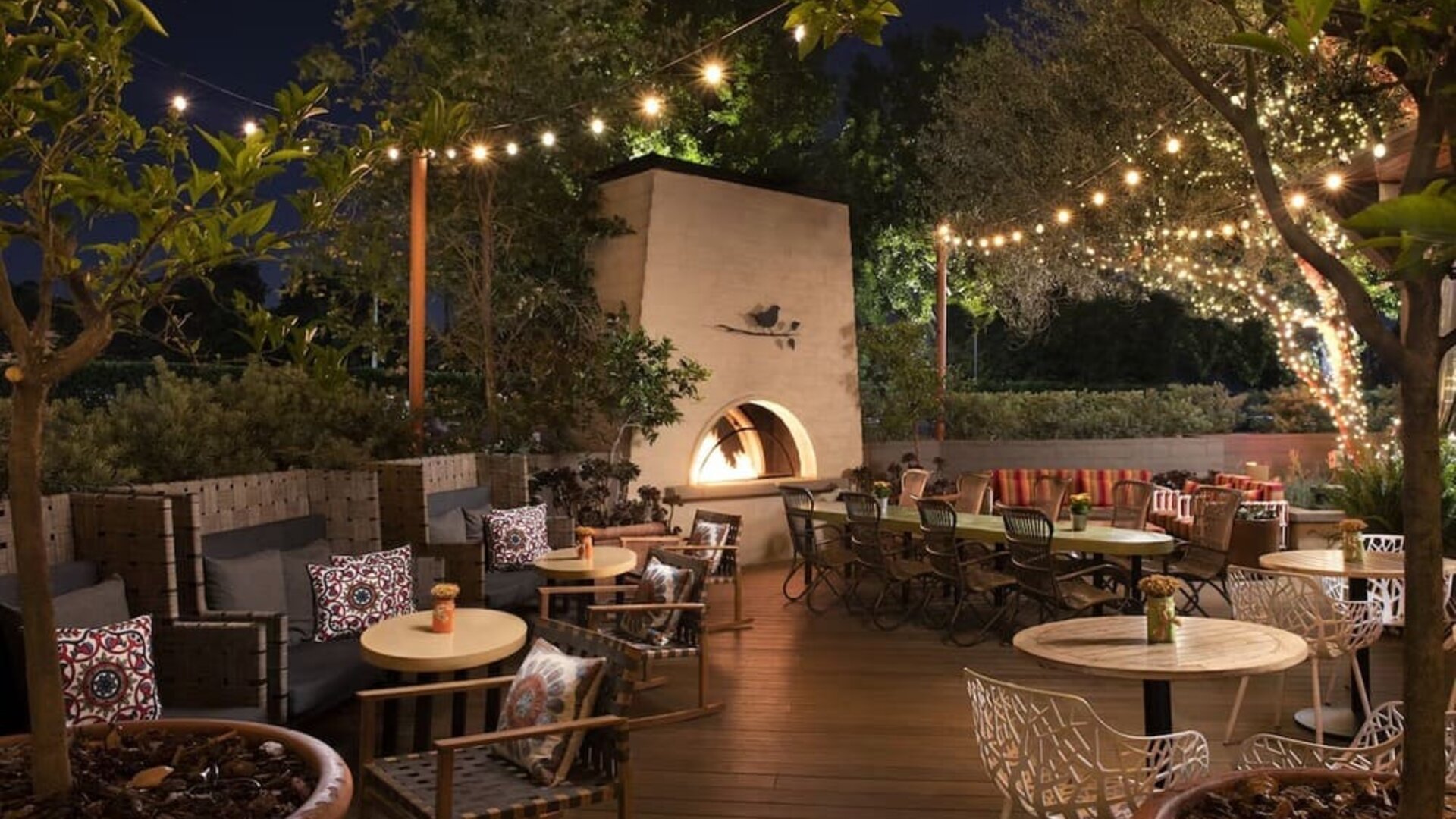 Charming outdoor dining patio with string lighting, fireplace feature, and garden-inspired seating at The Garland.