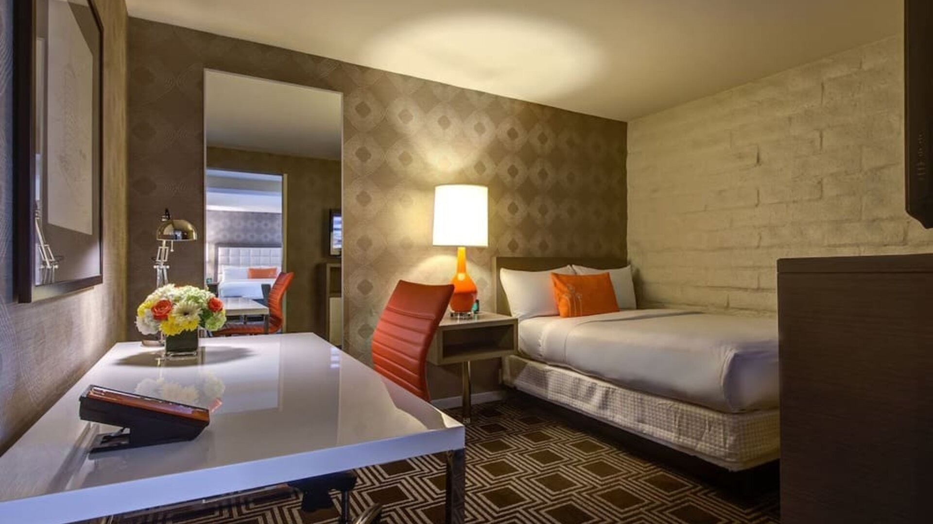 Contemporary guest room at The Garland featuring a comfortable bed, dedicated workspace, warm lighting, and modern mid-century inspired décor.