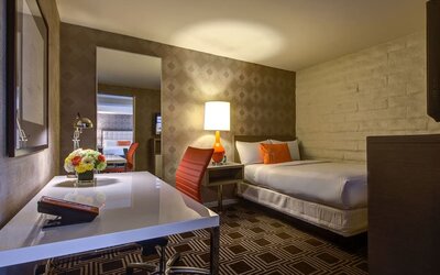 Contemporary guest room at The Garland featuring a comfortable bed, dedicated workspace, warm lighting, and modern mid-century inspired décor.