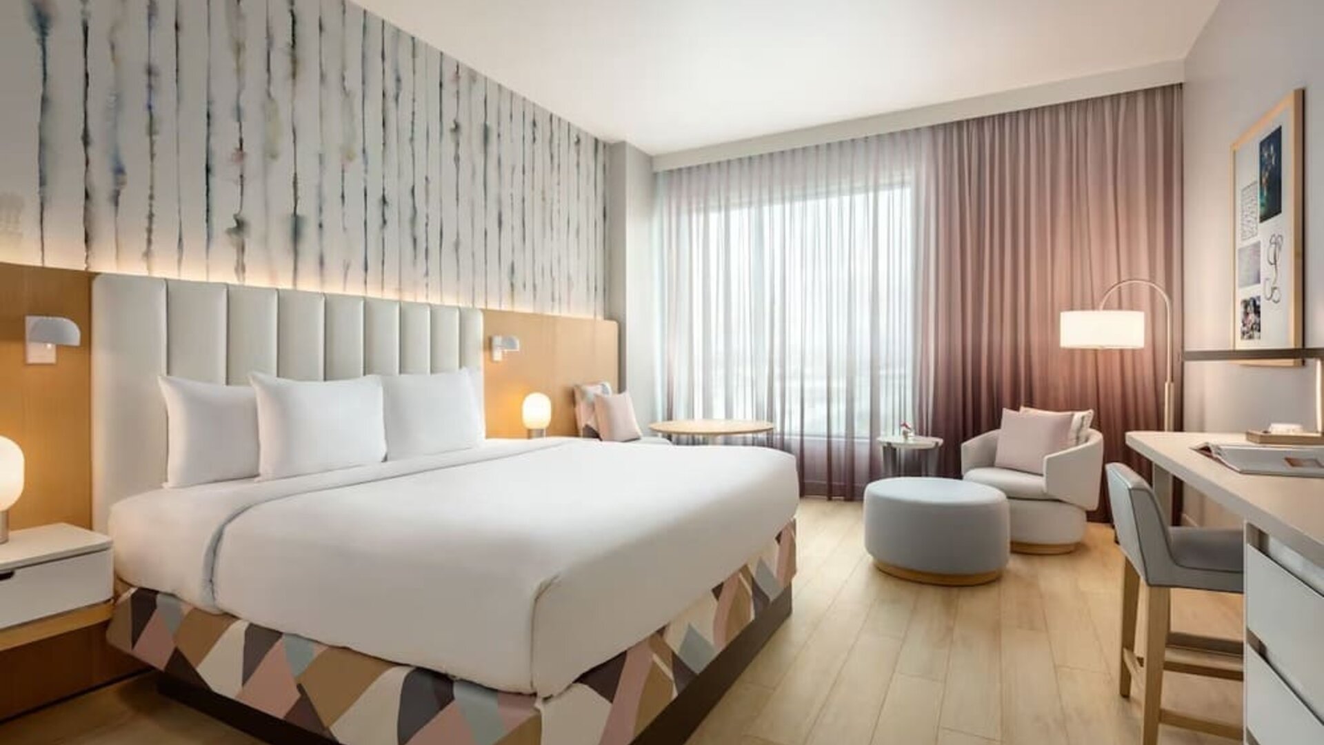 Guest room with a king-size bed, seating area, work desk, and floor-to-ceiling windows offering a bright and relaxing environment.