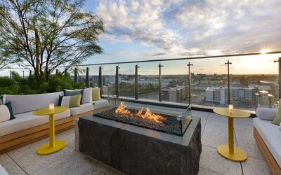 Rooftop terrace with fire pit seating, city views, and comfortable outdoor lounges, ideal for social gatherings and sunset relaxation.
