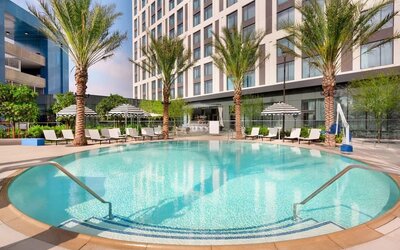 Resort-style pool area surrounded by palm trees, lounge chairs, and private seating areas, creating a relaxing outdoor retreat.