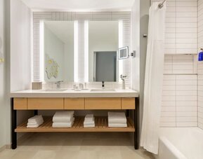 Guest bathroom with dual illuminated mirrors, spacious vanity, and modern bath amenities designed for comfort and convenience.