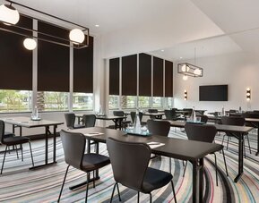 Contemporary meeting room at The Viv Hotel, Anaheim, A Tribute Portfolio Hotel featuring flexible conference-style seating, natural light, modern lighting fixtures, and presentation facilities for business meetings and events.