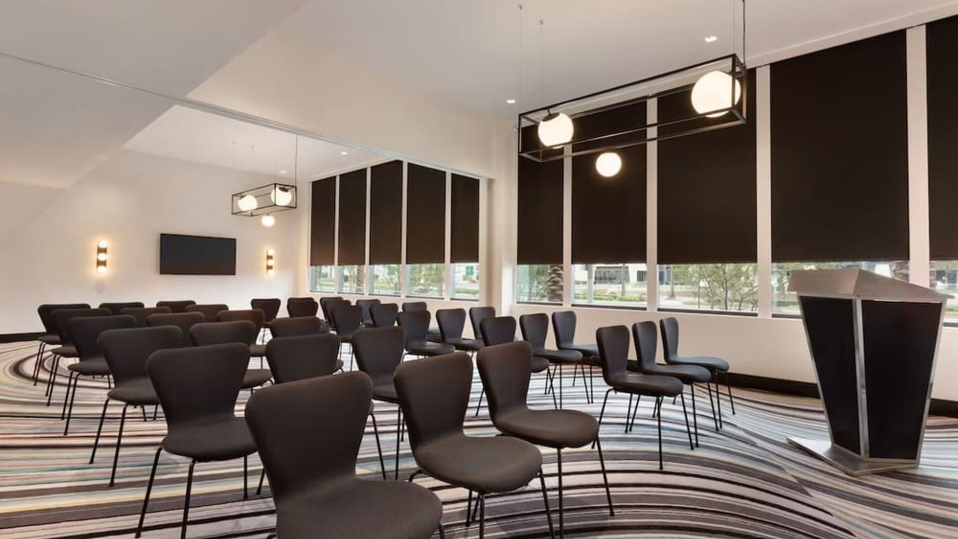 Meeting and event room equipped with modern seating arrangements and presentation facilities suitable for business meetings and small conferences.
