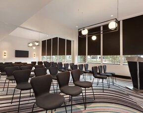 Meeting and event room equipped with modern seating arrangements and presentation facilities suitable for business meetings and small conferences.