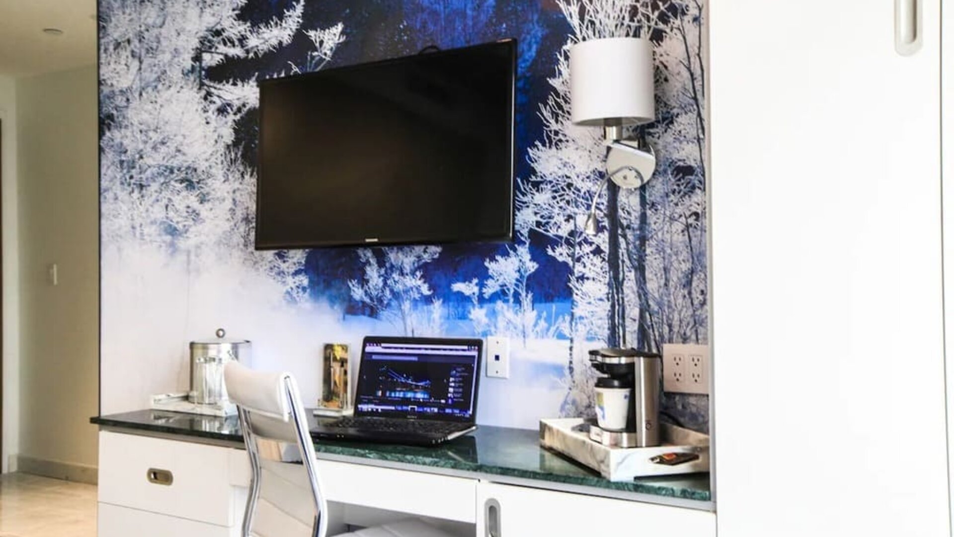 In-room workspace with desk, ergonomic seating, coffee station, storage cabinetry, and entertainment amenities ideal for business and leisure travelers.