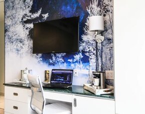 In-room workspace with desk, ergonomic seating, coffee station, storage cabinetry, and entertainment amenities ideal for business and leisure travelers.