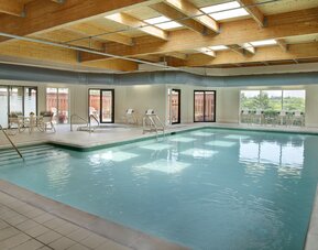 Relaxing indoor pool with lounge chairs at Courtyard By Marriott Toronto Airport.