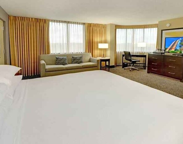 King room with king bed, TV screen, desk and sofa at the Hilton Orlando-Altamonte Springs.