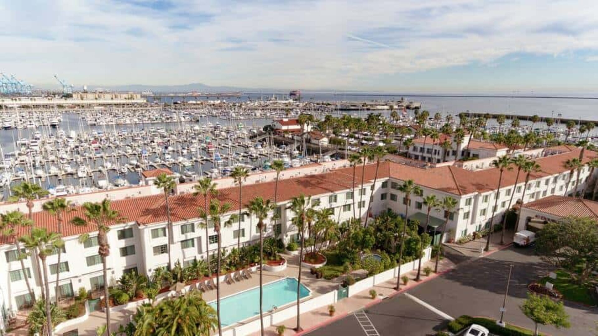 Aerial view of San Pedro Hilton Double Tree and the marina filled with boats behind it.