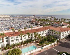 Aerial view of San Pedro Hilton Double Tree and the marina filled with boats behind it.