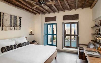 Bright room with king size bed, desk and windows at the Al Seef Heritage Hotel Dubai, Curio Collection by Hilton.
