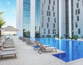 Beautiful outdoor pool with pool chairs at the Hampton Dubai Airport