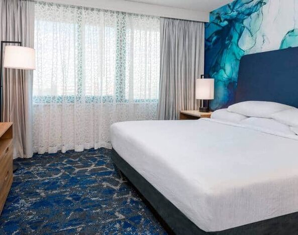 Spacious room with king size bed, tv and media console at the Embassy Suites by Hilton Tampa USF