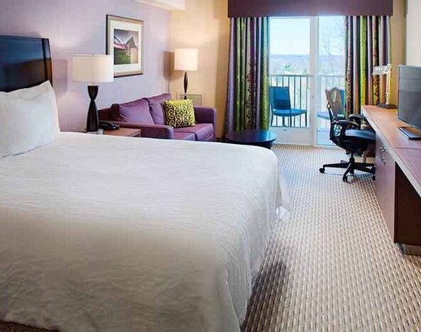 Comfortable king size bed, sofa and desk in a hotel room at the Hilton Garden Inn Hartford North/Bradley Intl Airport.