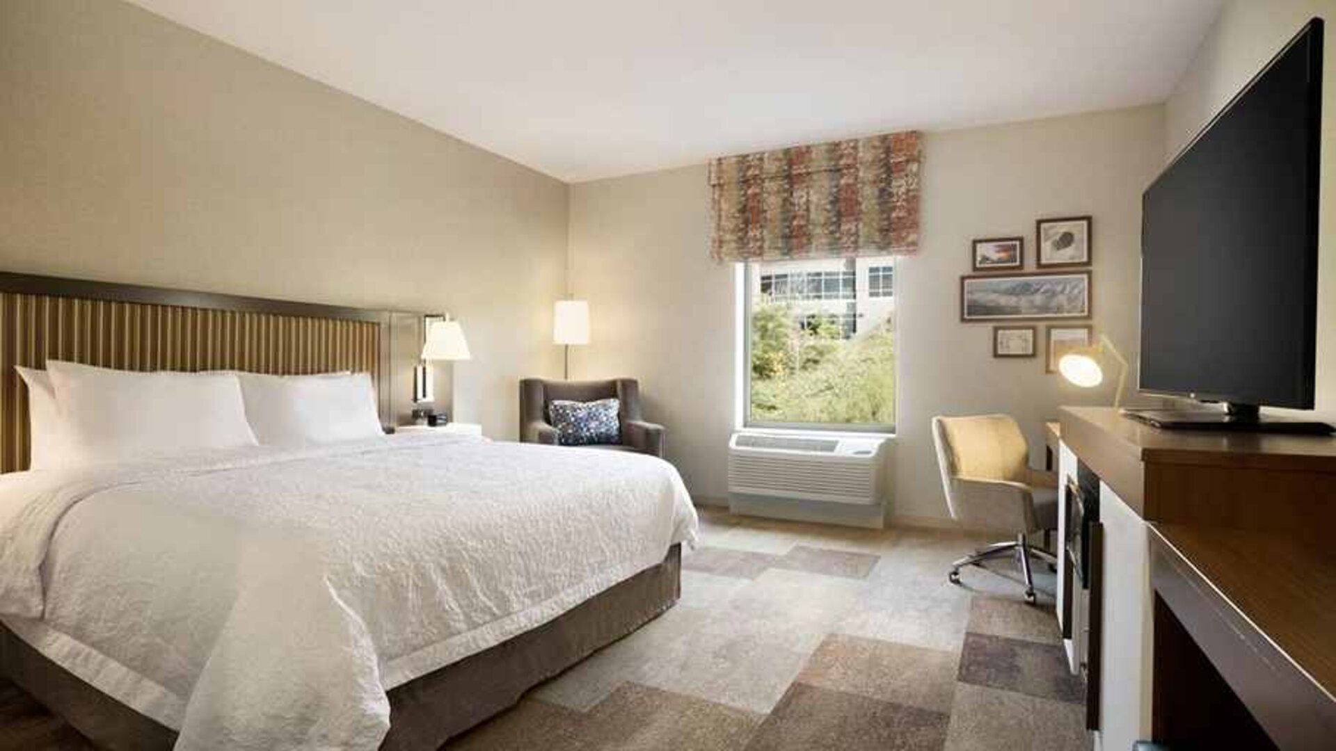 Bright-lit king-sized bed with TV and work desk at Hampton Inn By Hilton, Salt Lake City Cottonwood.
