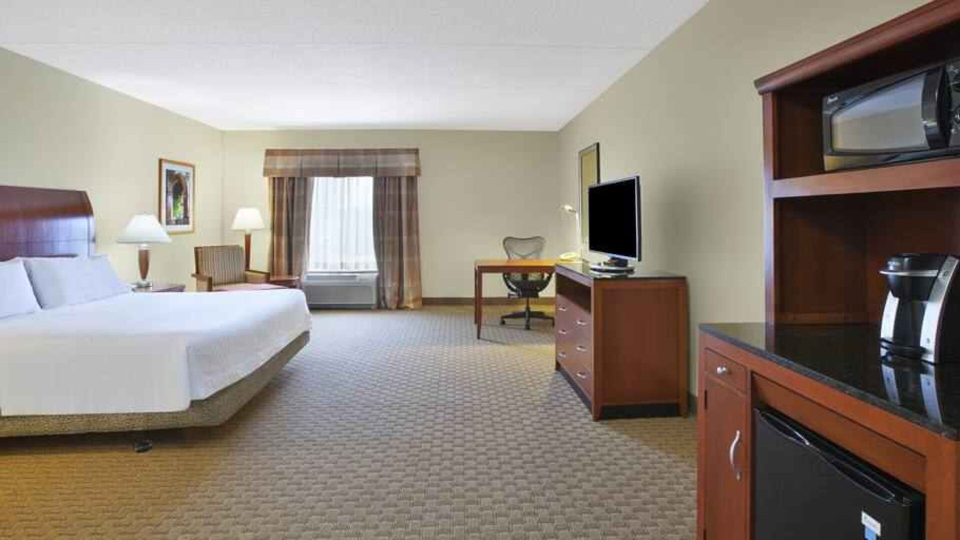 Spacious and bright king guestroom with TV and desk at the Hilton Garden Inn Clarksburg.
