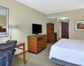 King size bed, desk and TV screen in a hotel room at the Hilton Garden Inn Clarksburg.