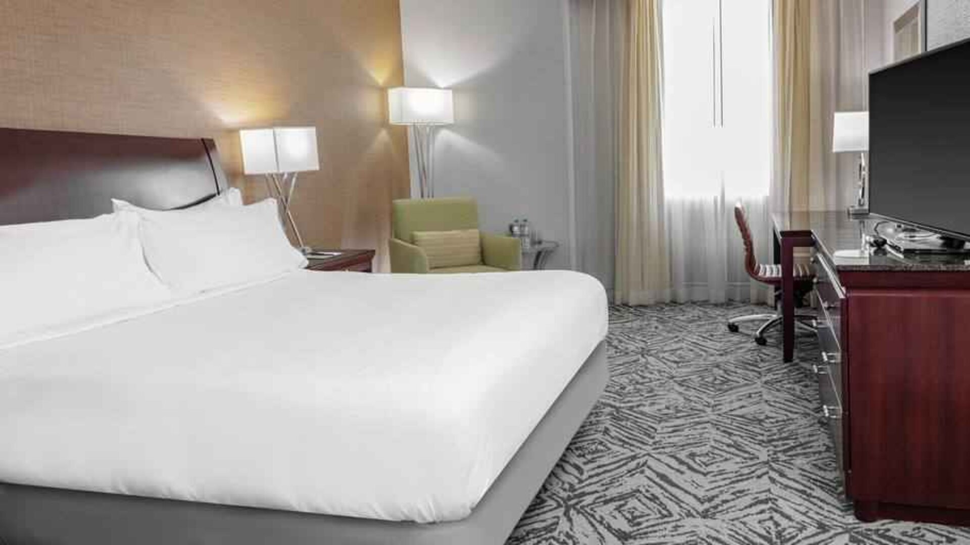 King size bed, TV screen and desk in a hotel room at the DoubleTree by Hilton Omaha-Downtown.