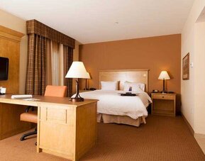 Hotel room with king size bed and working station at the Hampton Inn & Suites Riverton, WY.