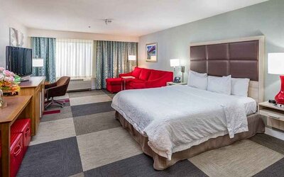 Spacious king room with work area and lounge at Hampton Inn San Francisco Airport.