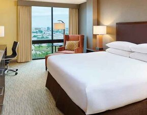 King size bed, desk and TV screen in a king guestroom at the Hilton San Antonio-Airport.