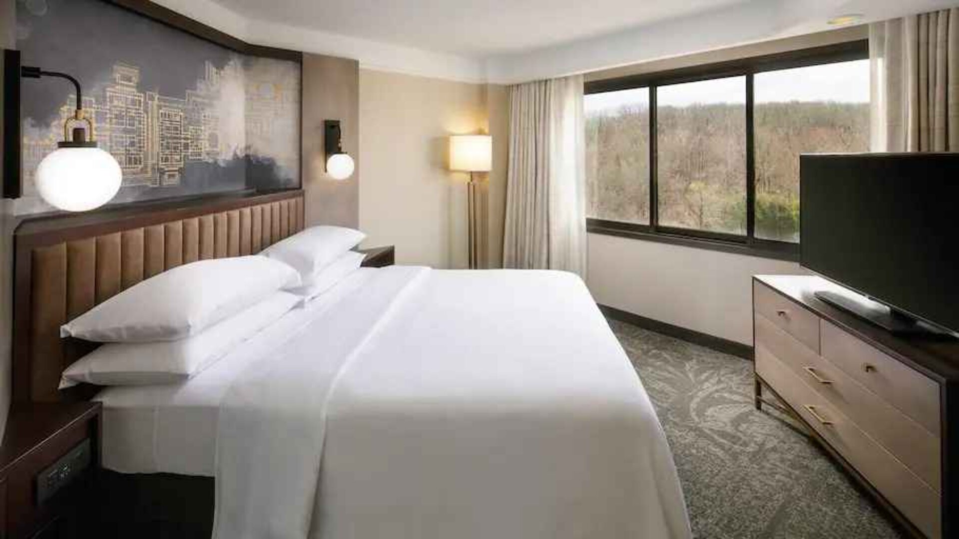 Bright king bedroom with window and TV screen at the Embassy Suites by Hilton Tysons Corner.