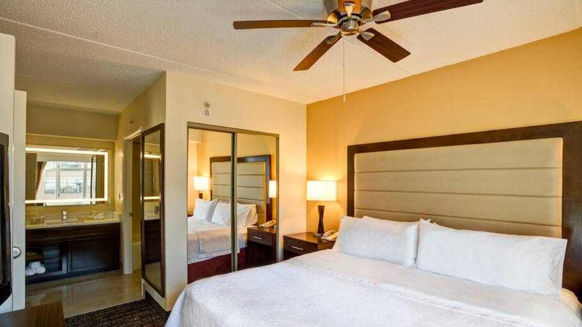 King size bed, fan and mirror in a king guestroom at the Homewood Suites by Hilton Washington, D.C. Downtown.