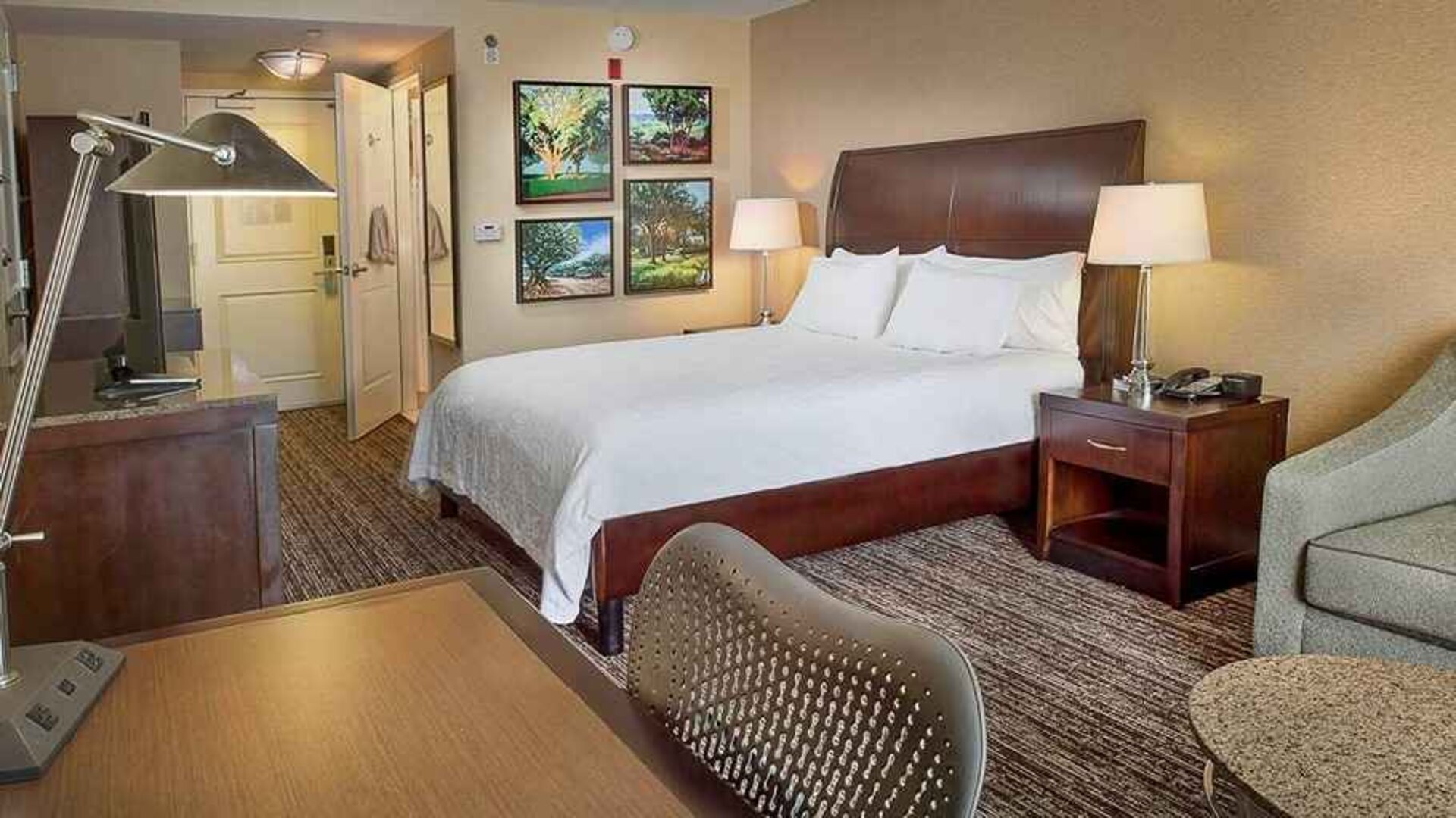 spacious king bedroom with TV, lounge area, and work desk ideal for working remotely at Hilton Garden Inn St. Louis Airport.