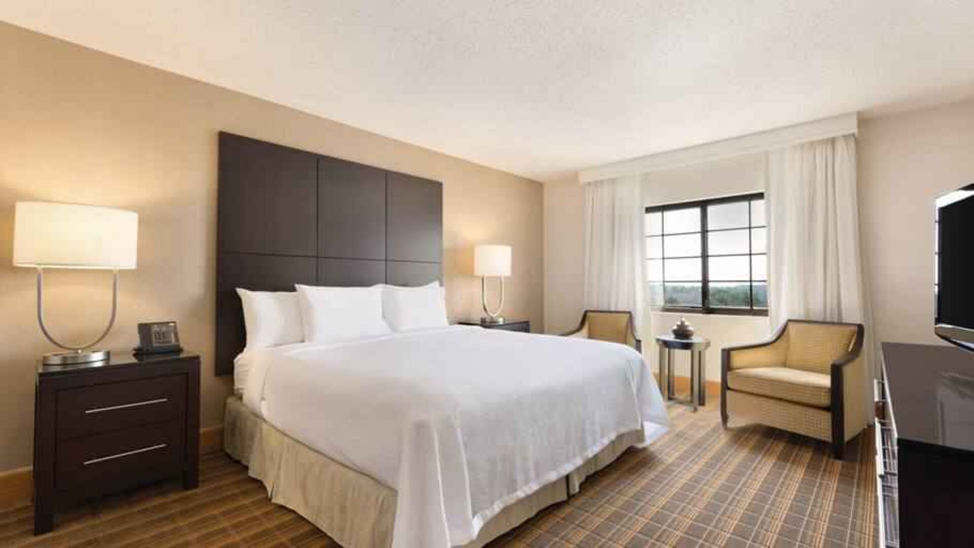 Comfortable king bedroom with window at the Embassy Suites by Hilton Greenville Golf Resort Conference Center