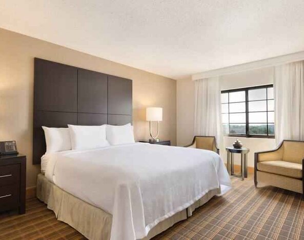 Comfortable king bedroom with window at the Embassy Suites by Hilton Greenville Golf Resort Conference Center