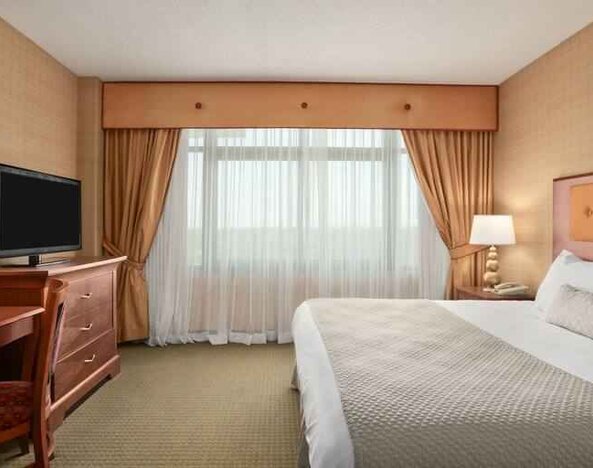 King bedroom with TV screen and desk at the Embassy Suites by Hilton Hot Springs Hotel & Spa.